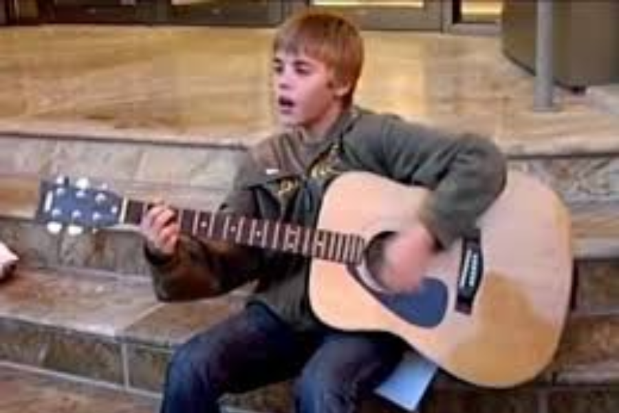 Young justin bieber as a kid playing guitar inside a mall