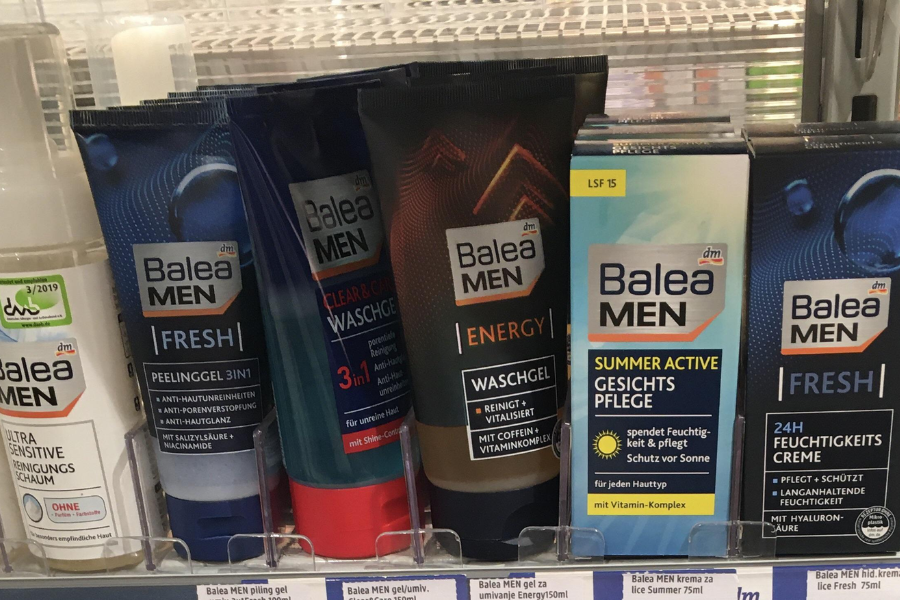 A shelf display of various Balea MEN skincare products, including face wash gels, exfoliating scrubs, moisturizing creams, and sun protection, labeled in German and designed for different skin needs like freshness, energy, and sensitivity.