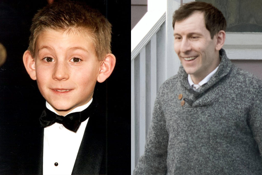Side-by-side image of a boy and a man. On the left, a young boy with short light brown hair and prominent ears wears a black tuxedo with a bow tie, posing at a formal event. On the right, an adult man with short dark hair and a big smile wears a gray sweater with button details, standing outside near a porch.