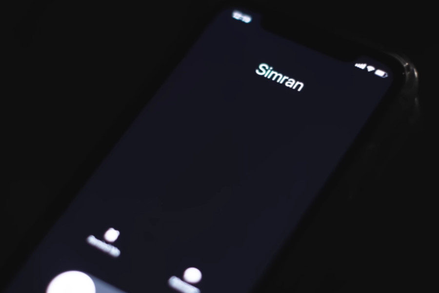A smartphone screen in a dark setting shows an incoming call from a contact named "Simran." The interface displays options to accept or decline the call.